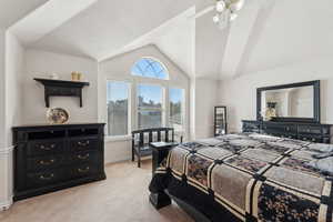 Bedroom with light colored carpet, lofted ceiling, and a ceiling fan
