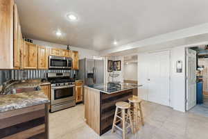 Kitchen featuring stainless steel appliances, a kitchen island, a breakfast bar, recessed lighting, and light tile patterned flooring