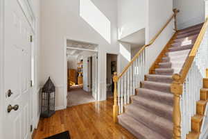 Entrance foyer featuring a towering ceiling, stairs, and wood finished floors