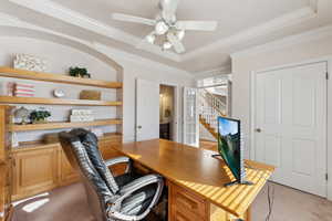 Office space with light colored carpet, a ceiling fan, ornamental molding, and built in desk