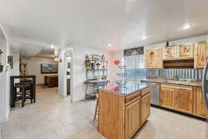 Kitchen featuring stainless steel dishwasher, a center island, recessed lighting, a breakfast bar area, and light tile patterned floors