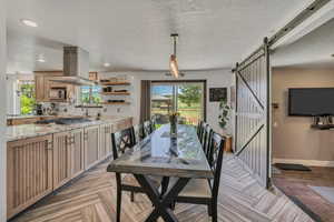 Dining room featuring a barn door, healthy amount of natural light, a textured ceiling, and recessed lighting