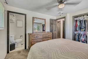 Bedroom with carpet, connected bathroom, a closet, ceiling fan, and tile patterned floors