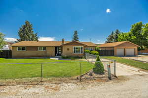 Ranch-style house featuring brick siding, a fenced front yard, a chimney, and driveway