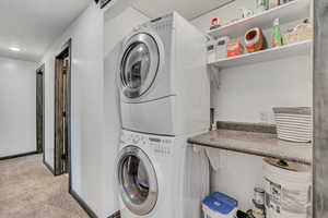 Laundry room featuring stacked washer / drying machine and carpet flooring