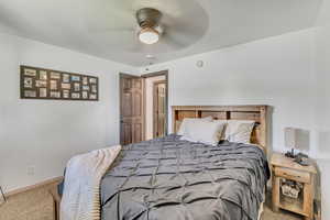 Carpeted bedroom with a ceiling fan and baseboards