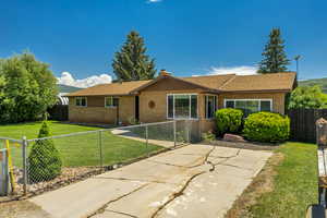 Ranch-style house featuring brick siding, a fenced backyard, a chimney, and a patio