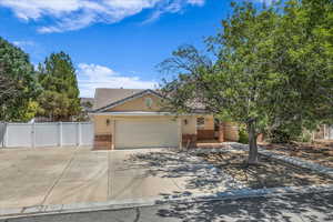 View of property hidden behind natural elements featuring brick siding, a gate, a garage, concrete driveway, and a tiled roof