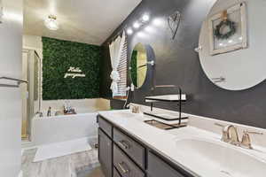 Full bathroom featuring a garden tub, a stall shower, double vanity, a textured ceiling, and wood finished floors