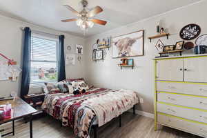 Bedroom featuring wood finished floors, multiple windows, ornamental molding, and a ceiling fan