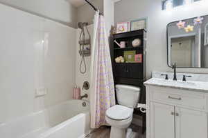 Full bathroom featuring vanity, wood finished floors, and shower / bath combination with curtain