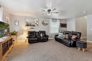 Living room with a ceiling fan and carpet flooring