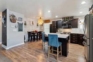 Kitchen with stainless steel appliances, a center island, light countertops, a breakfast bar area, and healthy amount of natural light