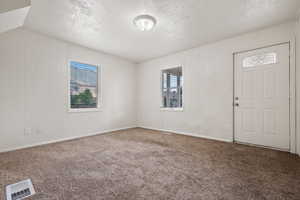 Carpeted entryway with a textured ceiling and baseboards