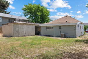 Rear view of house featuring a yard and roof with shingles