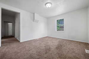 Unfurnished room featuring carpet flooring and a textured ceiling