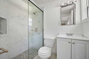 Full bath with a marble finish shower, vanity, and a textured ceiling
