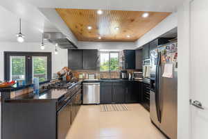 Kitchen with stainless steel appliances, a sink, open shelves, plenty of natural light, and wood ceiling