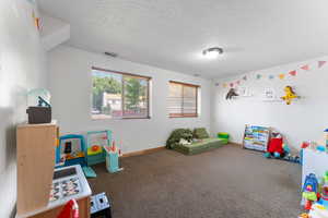 Game room with carpet floors, a textured ceiling, and baseboards