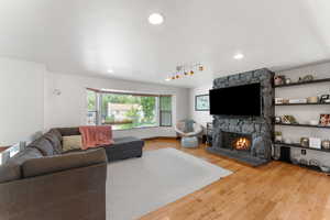Living area featuring hardwood / wood-style floors, a stone fireplace, and recessed lighting