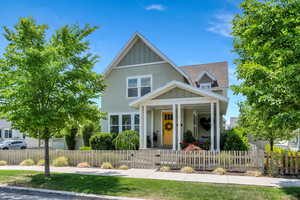 View of front of home with a porch, board and batten siding, roof with shingles, a gate, and a fenced front yard