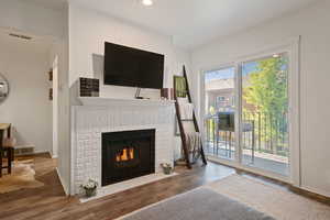Living room with wood finished floors, a fireplace, and recessed lighting