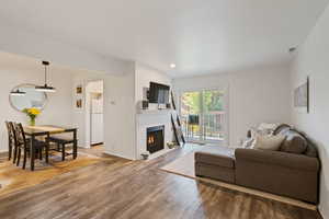 Living area with wood finished floors, a brick fireplace, and recessed lighting