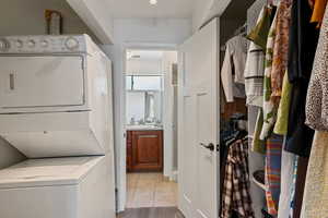Laundry room with estacked washer and dryer and light tile patterned floors