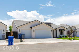 View of front of home with a tile roof, an attached garage, board and batten siding, and brick siding