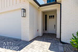 Property entrance featuring board and batten siding, brick siding, and a garage