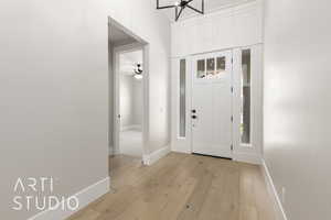 Entryway featuring light wood-style floors, baseboards, a chandelier, and a ceiling fan