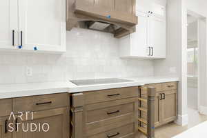 Kitchen with range hood, white cabinetry, and light countertops
