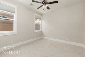 Carpeted spare room featuring ceiling fan and baseboards