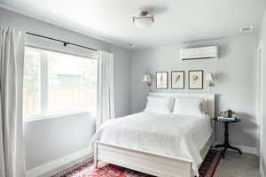 Bedroom featuring a wall mounted air conditioner and baseboards