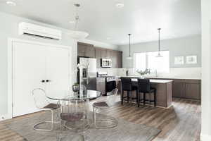 Dining area with a wall unit AC, wood finished floors, and recessed lighting