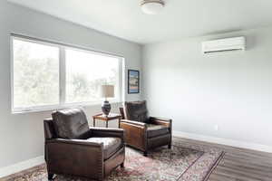 Living area featuring an AC wall unit, wood finished floors, and baseboards