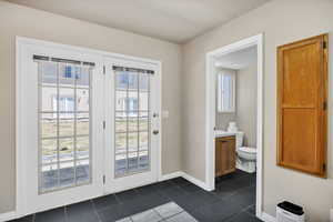 Doorway with dark tile patterned floors and baseboards