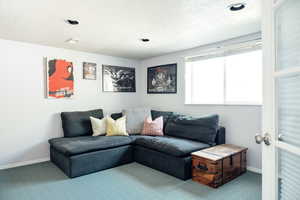 Living area with carpet, a textured ceiling, and baseboards