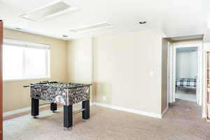 Rec room featuring attic access, carpet, and baseboards