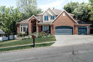 Traditional-style house featuring roof with shingles, brick siding, an attached garage, and driveway