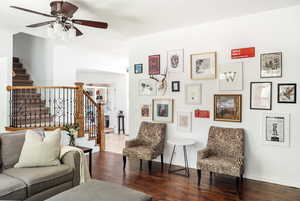Living area with wood-type flooring, baseboards, stairway, and ceiling fan