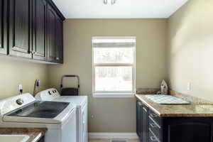 Washroom featuring cabinet space, washer and clothes dryer, plenty of natural light, and light tile patterned flooring