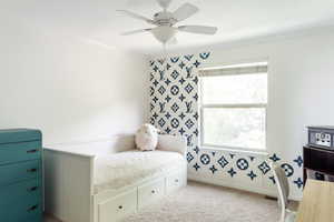 Bedroom with ornamental molding, carpet floors, pattern painted walls, and ceiling fan
