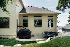 Back of house featuring a shingled roof, a patio, and stucco siding