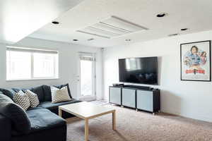 Living room with a textured ceiling, attic access, light colored carpet, and baseboards