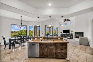 Kitchen featuring stainless steel dishwasher, light tile patterned floors, ceiling fan, dark brown cabinetry, and hanging light fixtures