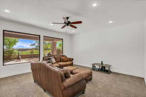 Living area with light carpet, recessed lighting, and a ceiling fan