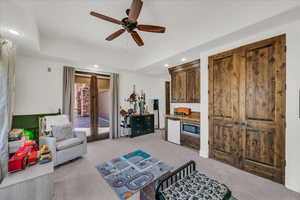 Living area featuring light carpet, recessed lighting, a ceiling fan, and a tray ceiling