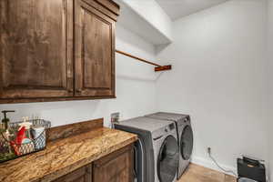 Laundry room with cabinet space, washer and clothes dryer, and light tile patterned flooring