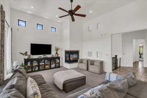 Living room featuring a towering ceiling, healthy amount of natural light, ceiling fan, recessed lighting, and a multi sided fireplace